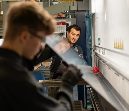 Mitarbeiter prüft Bauteil während Maschinenbearbeitung