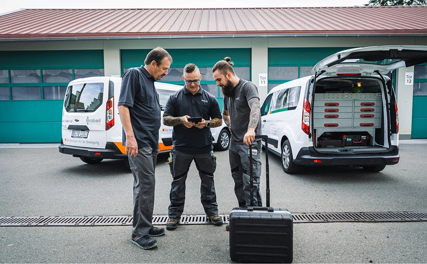 Servicetechniker mit Tablet vor Firmenfahrzeug