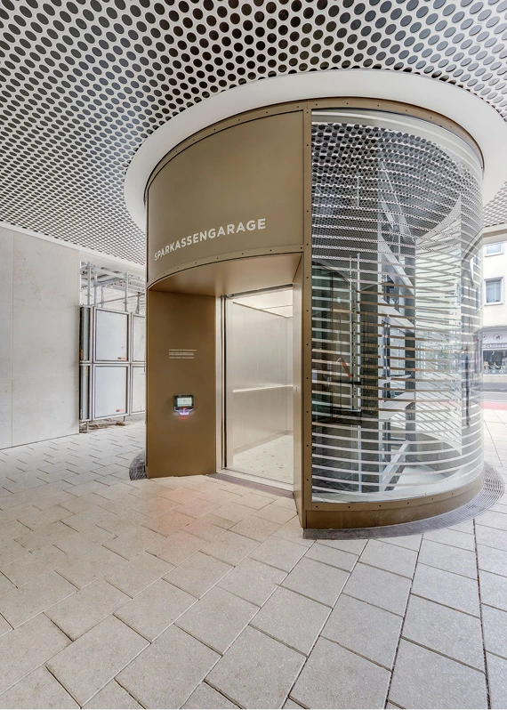 Runder Panoramaaufzug mit bronzefarbener Verkleidung in moderner Lobby