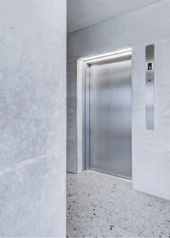 Moderner Edelstahlaufzug in Betonoptik-Wand